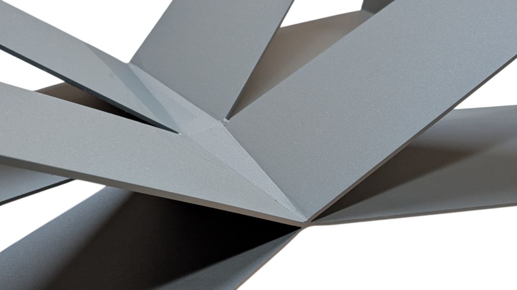 Close-up of gray metal beams converging at a central joint to form an abstract geometric sculpture.
