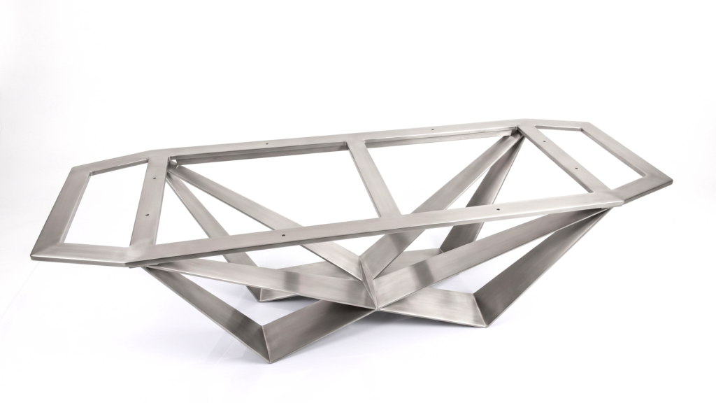 Angular stainless steel sculpture comprised of interlocking rectangular frames forming a geometric lattice on a white background